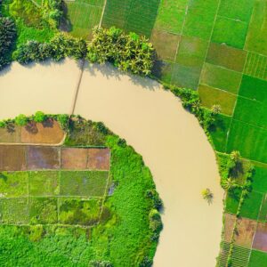 Aerial image showcasing lush green farmland and a winding river, highlighting rural agriculture.